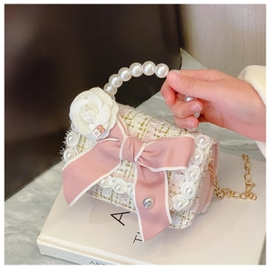Detail of pink tweed girl handbag featuring large bow, camellia flower and pearl handle