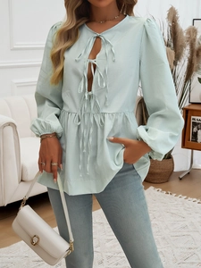 Close-up of light green striped blouse featuring bow ties and lantern sleeve details
