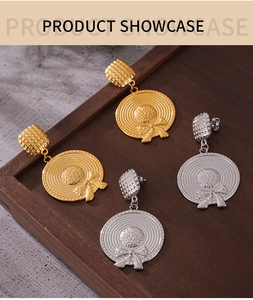 Close-up detail of gold and silver straw hat earrings with bows on a wooden tray