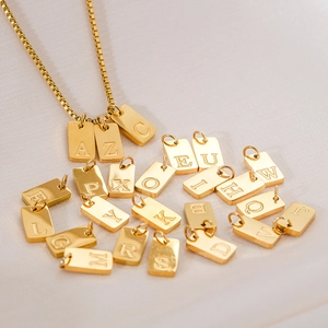 Gros plan de pendentifs carrés plaqués or 18 carats sur un fond en soie blanche