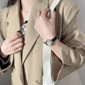 Close-up of luxury women's watch with Mickey-shaped gold case and black leather strap