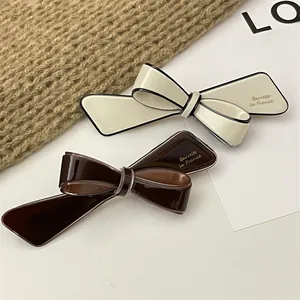 Detail of French style 3D bow hair clips in cream and dark brown on a cozy knit background