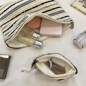 Detail of striped canvas makeup bags showing the textured fabric and zipper closure