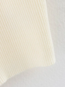 Primer plano del tejido de punto crema con textura de canalé y artesanía detallada