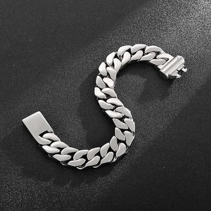 Macro shot of silver stainless steel Cuban link bracelet on textured black background