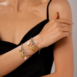Detail of mixed gold and silver ocean bracelet with pearl and sea creature charms on wrist