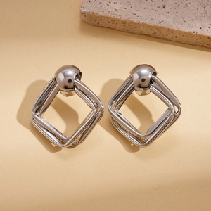 Détail de boucles d'oreilles carrées argentées sur pierre avec éclairage naturel