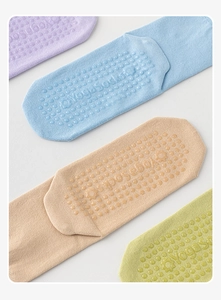 Detail of four colorful non-slip yoga socks with silicone grip dots on white background