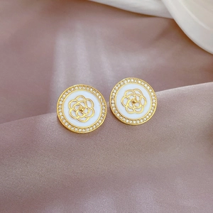 Close-up of camellia earrings with gold circular frame and sparkling zircon inlay