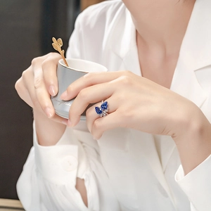 Elegant pear cut blue sapphire open ring with double diamond accents on a female hand