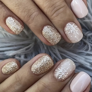 Nahaufnahme von pinkfarbenen Nägeln mit Goldglitzer und festlichen Schneeflocken