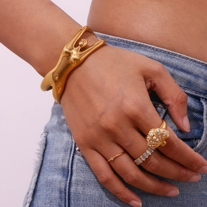 Detail of 18K gold-plated body shape bracelet and shell ring worn on denim background