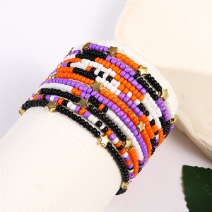 Detail of handmade beaded bracelet set with purple and orange beads and gold star charms