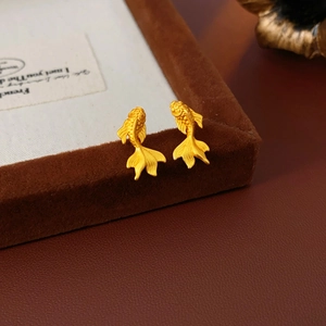 Gros plan de boucles d'oreilles carpe koï dorées avec texture d'écailles sur velours