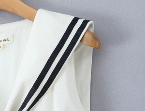 Detail of nautical sailor collar on white dress with black stripes and brand label
