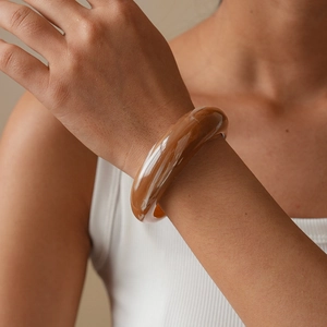 Close-up of a minimalist amber resin cuff bracelet with polished finish on wrist