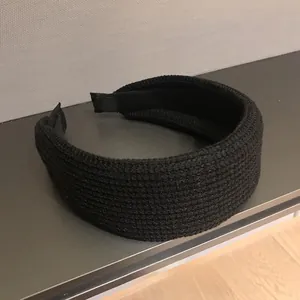 Close-up of black knitted headband showing thick ribbed texture and woven details