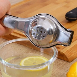 Manual stainless steel lemon squeezer pressing fresh juice into a glass bowl with lemons