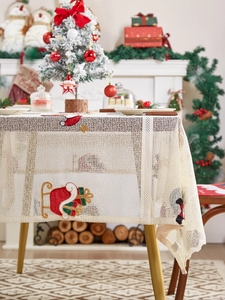 Detailed close-up of Santa Claus embroidery and lace texture on festive Christmas tablecloth