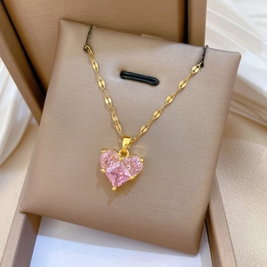 Close-up of gold titanium necklace with heart pendant and pink cubic zirconia on velvet box