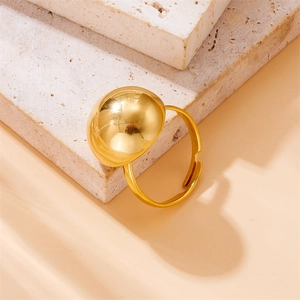Dettaglio di un anello regolabile placcato oro con una grande sfera di metallo lucido