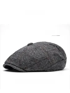Close-up detail of light gray newsboy cap with orange herringbone wool pattern