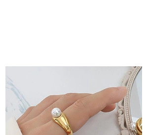 Close-up of a gold geometric ring with a white pearl on a model's hand