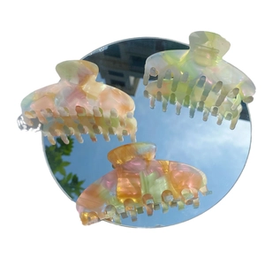 Three holographic marble acetate hair claws reflected on a mirror under a blue sky