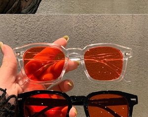 Detail view of square retro sunglasses featuring orange lenses and model specifications