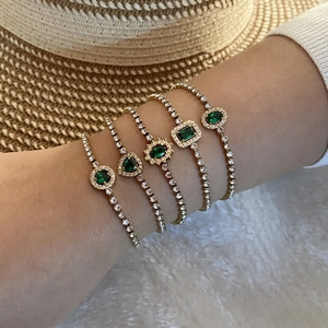 Détail d'un ensemble de cinq bracelets dorés avec pierres vert émeraude et zircons blancs