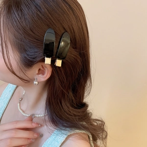 Close-up of black drop hair clips on hair with pearl earrings and textured green top