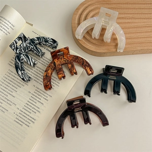 Five French acetate hair claws in marble and tortoiseshell patterns on wooden tray