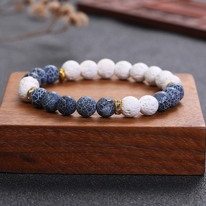 Retro beaded bracelet with white lava stone and gold rhinestone spacer on wood