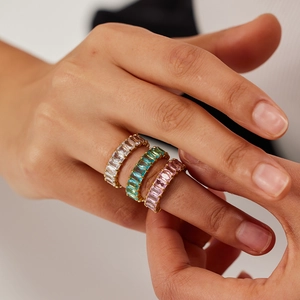 Trois bagues en acier doré avec zircons rectangulaires transparents, turquoise et roses