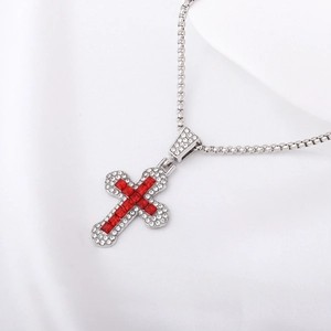 Close-up of a silver cross pendant with red gemstones on white silk background