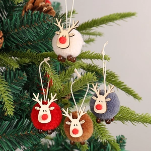 Christmas deer and sheep felt ball ornaments hanging on a festive green pine tree branch