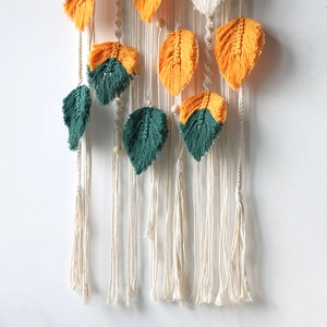 Detail of handmade macrame tapestry featuring woven leaf shapes and wooden beads