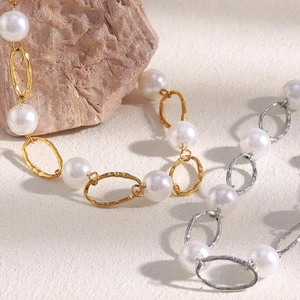 Minimalist hammered gold and silver links with pearl accents on a natural rock surface