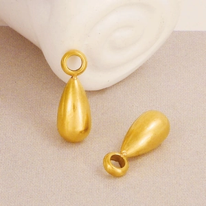 Macro shot of matte gold teardrop pendants for DIY jewelry making on textured fabric