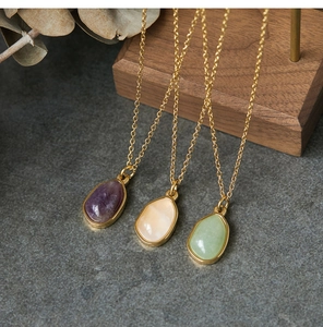 Close-up of teardrop gemstones in gold settings on gray stone with wooden accents