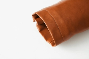 Detail view of the brown leather jacket cuff featuring precision stitching and smooth texture