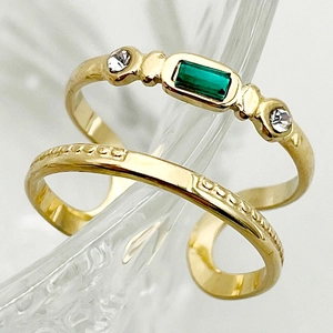 Macro shot of gold double-layer ring with green emerald cut gemstone and textured band