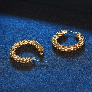 Retro gold hoop earrings with micro-bead texture on a deep blue textured surface