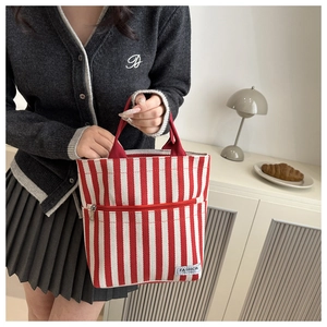 Detail of red and white striped canvas tote bag with front zipper pocket and fashion tag