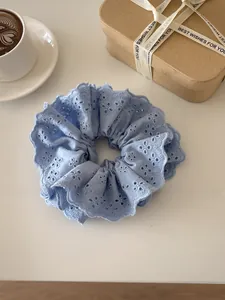 Close-up of light blue lace scrunchie with floral embroidery and ruffle texture