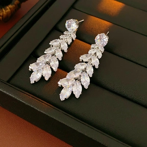 Detailed view of silver leaf-shaped tassel earrings with clear crystals in a black box