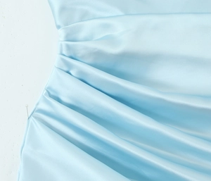Detailed view of light blue satin fabric with elegant pleated texture and draped neckline