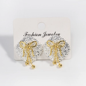 Detail of geometric square earrings with gold bow and tassel chains on display card