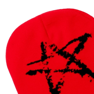 Detail of red knitted beanie featuring black star pattern and high-quality wool texture