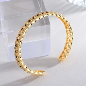 Macro detail of 18k gold plated open cuff bracelet with blue gemstone and white crystals